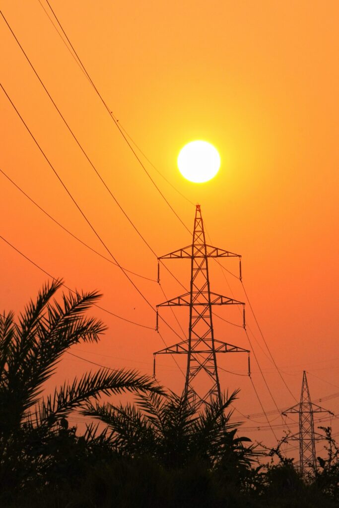 Silhouette of power lines at sunset with an orange sky in Kolkata, India.